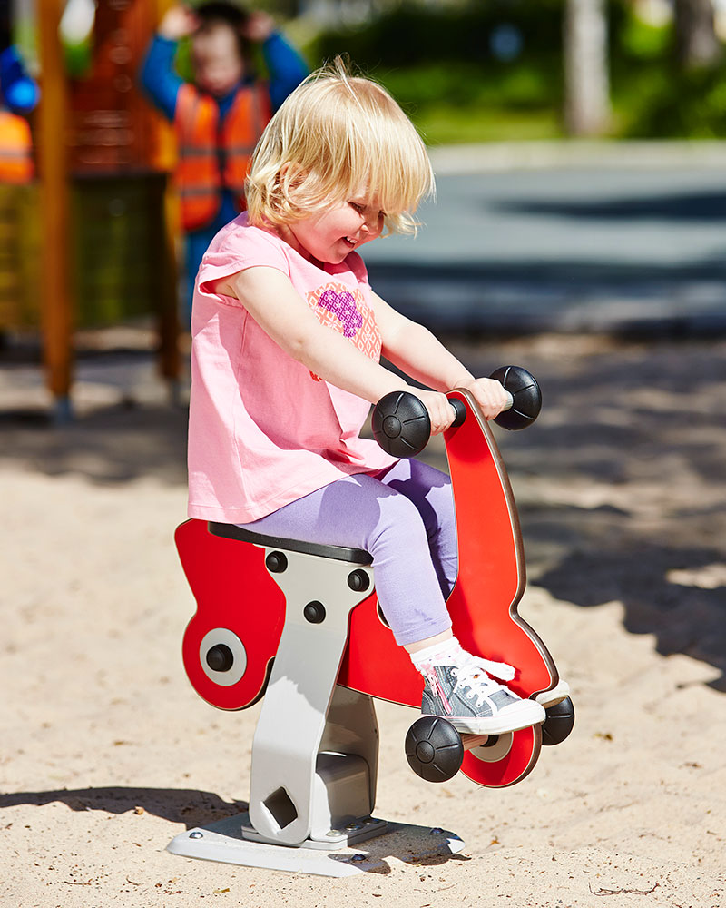 un bambino gioca su un dondolo del parco giochi.